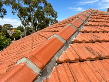 Freshly re-bedded and pointed ridge capping on a terracotta tile roof